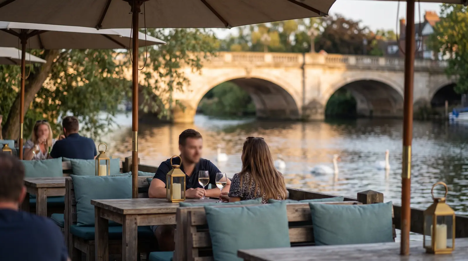 Illustrative scene of riverside café tables overlooking a stone bridge