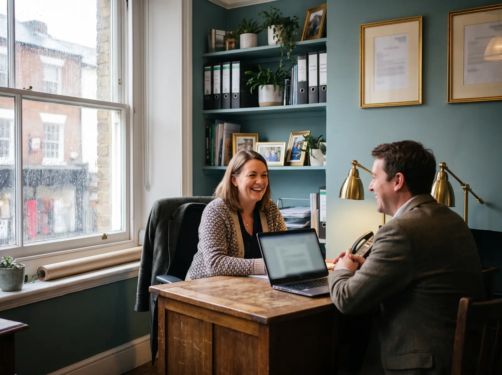 Illustrative scene of two people discussing work across a desk in a small accountancy office