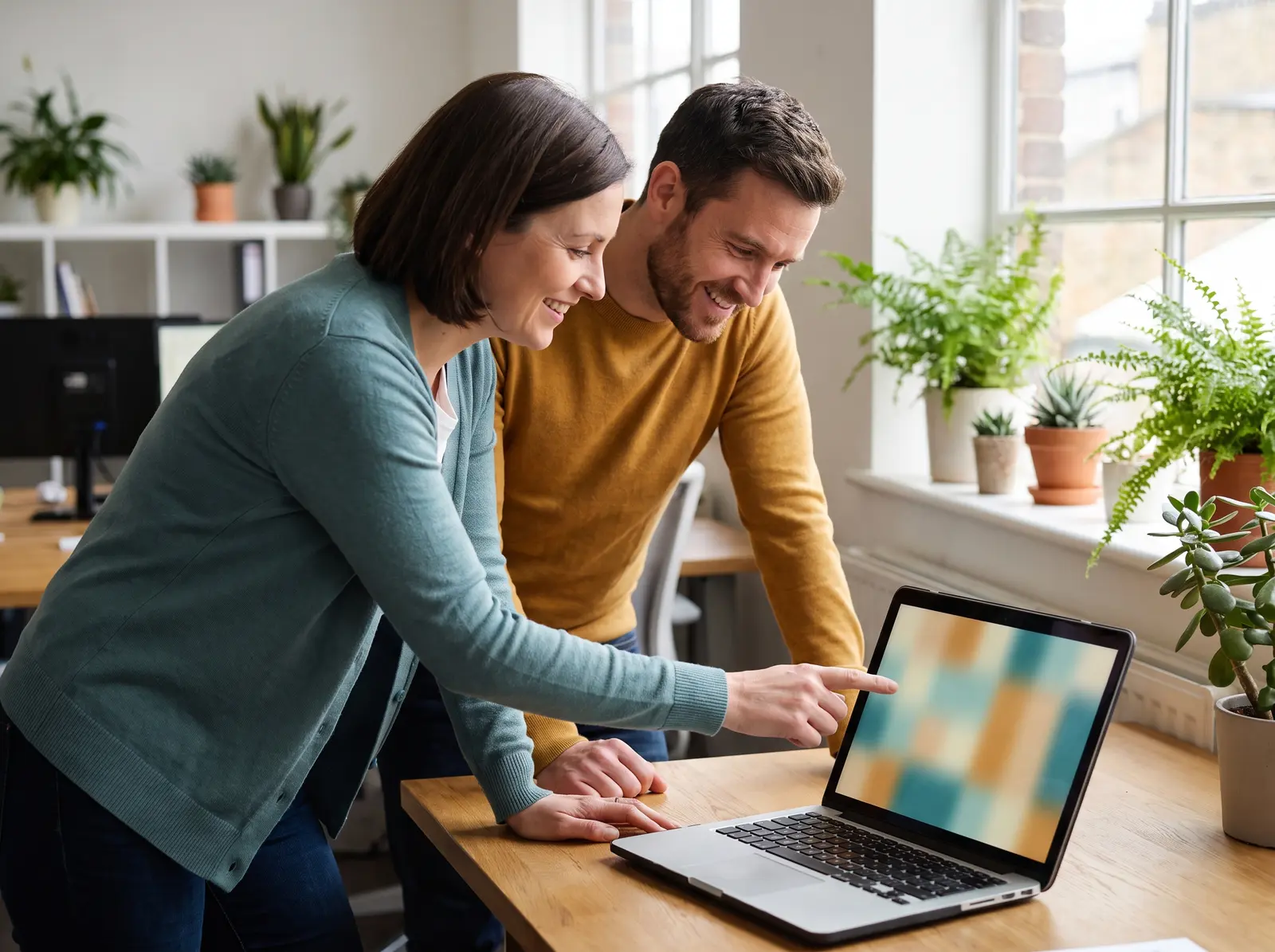 Two people looking together at a laptop in a bright room with houseplants
